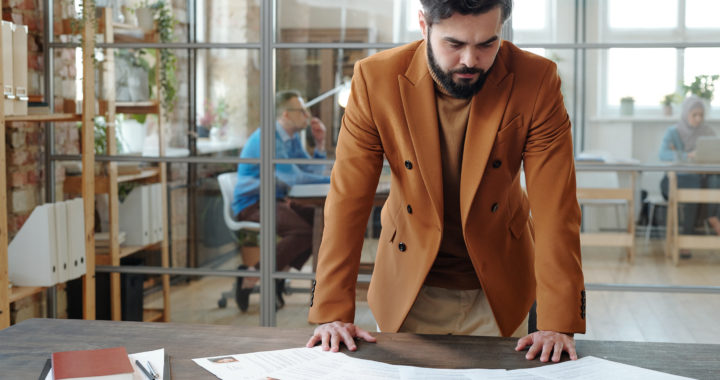 Serious hr manager bending over table while looking through resume
